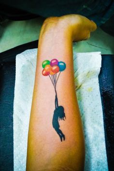 a person with a tattoo on their arm is holding balloons in the shape of a woman's leg