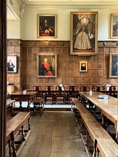 an empty dining room with wooden benches and paintings hanging on the wall behind it,