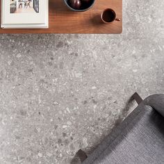 a wooden table topped with a bowl of fruit next to a cup of coffee and an open book