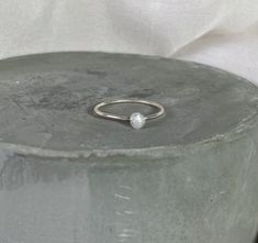 a silver ring with a white pearl on it sitting on top of a cement block