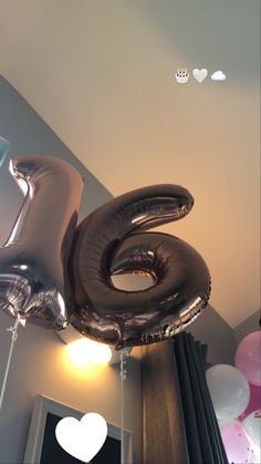 balloons are floating in the air near a number six balloon on a wall with hearts