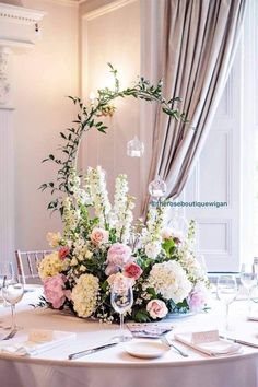 an elegant centerpiece with flowers and greenery is displayed on a round dining table