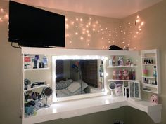 there is a vanity with lights in the mirror and shelving on the wall behind it