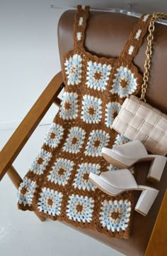 a crocheted dress and shoes are sitting on a chair next to a purse