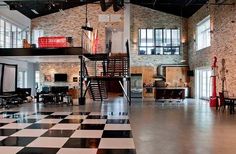 an industrial loft with black and white checkered flooring, exposed brick walls and stairs