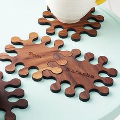 a wooden puzzle sitting on top of a table next to a potted plant and mug