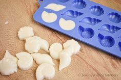 a blue tray filled with white icing next to an uncooked cookie sheet