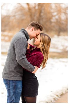 an engaged couple cuddles in the snow