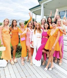 a group of women standing next to each other in front of a white and blue house