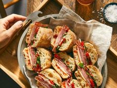 a pan filled with sandwiches on top of a wooden table next to a knife and fork