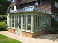 an orangery in the middle of a garden with glass doors and windows on each side