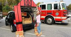 a woman standing in front of a fire truck with its open trunk and door opened