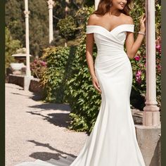 a woman in a white wedding dress standing next to a light pole and flowers on the ground