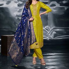 Elevate your festive style with our Green and Blue Silk Blend 3-Piece Festive Wear, a perfect blend of traditional elegance and modern charm. This luxurious ensemble includes: Silk Blend Kurta: The kurta is designed in a classy combination of green and blue, with exquisite gold weave motifs spread all over, adding a touch of richness and tradition. Plain Pants: The outfit is paired with simple, comfortable plain pants to balance the intricate gold motifs of the kurta, ensuring a sophisticated lo Elegant Zari Weaving Straight Kurta Set, Elegant Blue Banarasi Silk Set, Elegant Yellow Sets With Zari Weaving, Elegant Blue Sets With Zari Weaving, Fitted Sets With Zari Weaving For Celebration, Elegant Sets With Zari Weaving For Celebrations, Elegant Celebration Sets With Zari Weaving, Blue Dupatta, Festival Mode