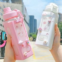 two people holding pink and white cell phones in front of each other with hello kitty designs on them