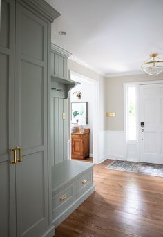 an empty room with wooden floors and gray cabinets in the corner, along with a white door