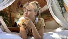 a woman sitting on top of a bed next to a window