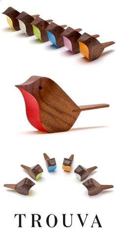 a wooden bird sitting on top of a piece of wood next to different colored birds