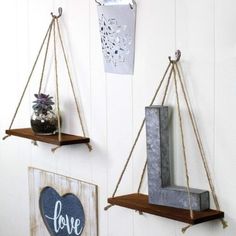 two wooden shelves with rope hanging from them and some decorations on the wall behind them