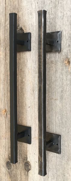 two black iron door handles on a wooden surface