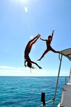 two people jumping into the water from a boat