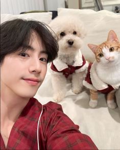 a woman is taking a selfie with two dogs and a cat on the bed