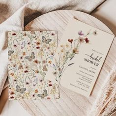 the wedding stationery is laid out on top of a wooden table with flowers and butterflies