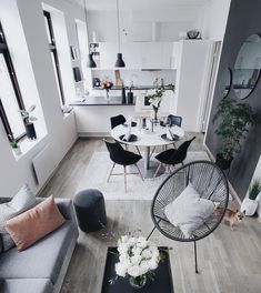 a living room filled with furniture next to a kitchen and dining room table on top of a hard wood floor