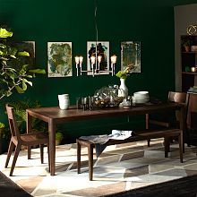 a dining room with green walls and white rug on the floor next to a wooden table