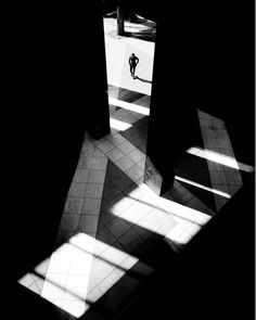 shadows cast on the floor and walls in an empty room with two people walking through it