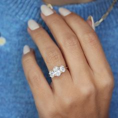 a woman's hand wearing a three stone ring