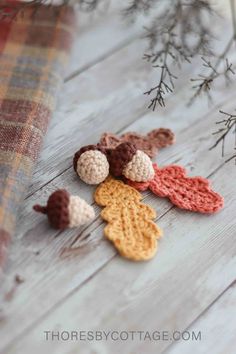 crocheted leaves are laying on the ground next to some pine cones and branches