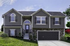 a two story house with gray siding and white trim on the front door is shown