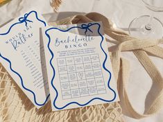 two blue and white wedding seating cards on a table with wine glasses, napkins and flowers