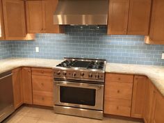 a stove top oven sitting inside of a kitchen next to wooden cabinets and stainless steel dishwasher