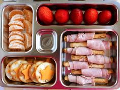 an open lunch box with fruit and pretzels in it, along with other food items