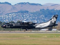 an air new zealand jet taking off from the runway at an airport with mountains in the background