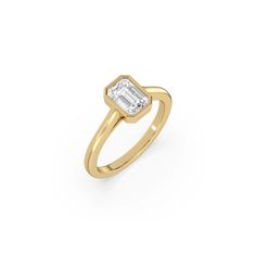 a yellow gold ring with an emerald cut diamond in the center, on a white background