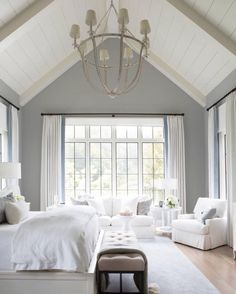 a large bedroom with white furniture and windows