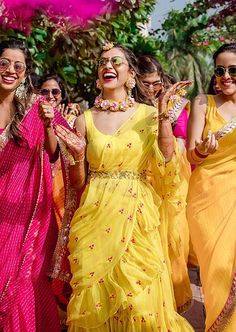 several women in yellow and pink dresses are dancing with their hands up to the sky