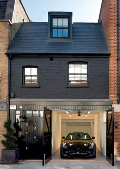 a car is parked in front of a house with an open garage door on the side