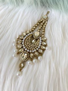 a close up of a brooch with pearls on it's side and a white fur background