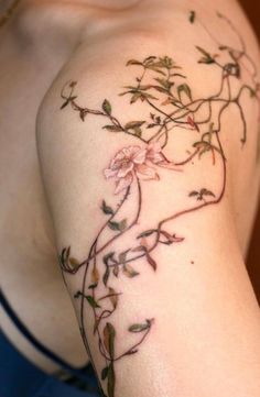 a woman's arm with flowers and vines tattooed on the back of her shoulder