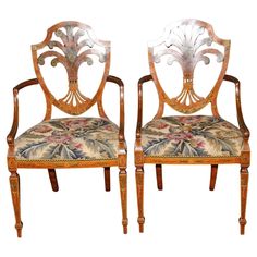 a pair of carved wooden chairs with floral upholster