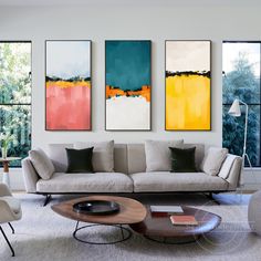 three paintings hang on the wall above a couch and coffee table in a modern living room