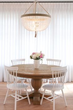 a dining room table with white chairs and a chandelier hanging from the ceiling