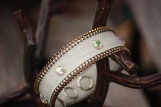 a pair of white and gold colored bracelets sitting on top of a piece of wood