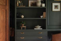 a room with green walls and shelves filled with books, vases and other items