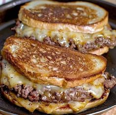 two grilled cheeseburgers sitting on top of a pan with melted cheese and meat