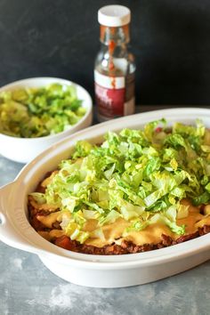 a casserole dish with lettuce and sauce in the middle on a table